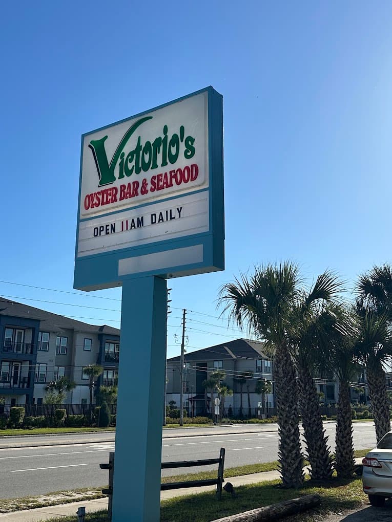 Victorio's Titusville road sign with palm trees — Open 11AM Daily